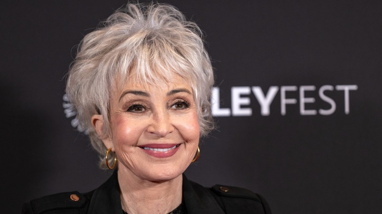 Annie Potts smiling in a black coat in 2024.