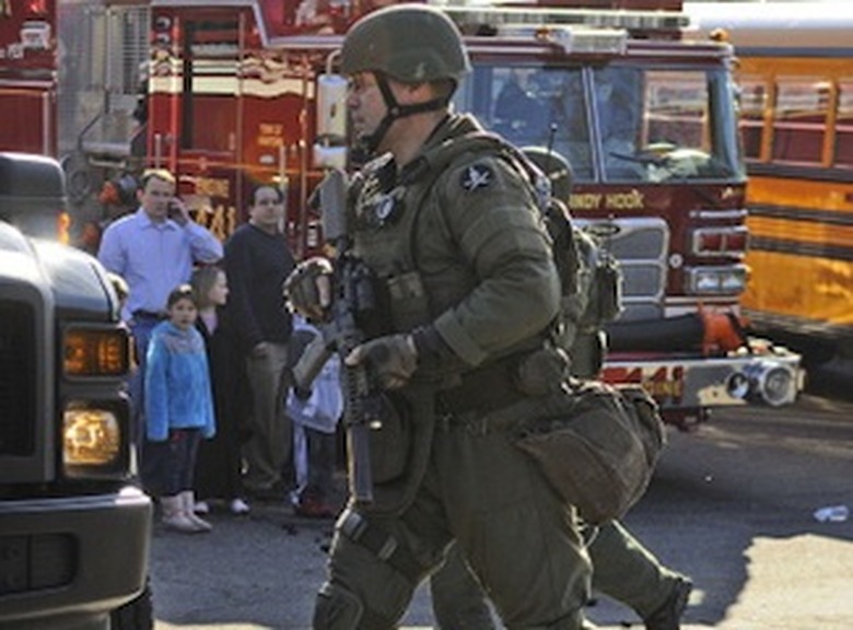 SWAT team member runs to a police car as Sandy Hook Elementary School is evacuated after a shooting